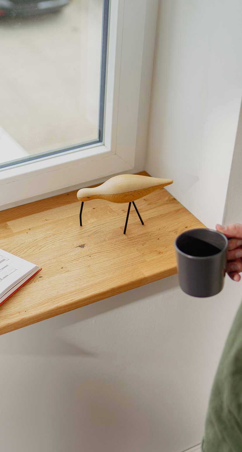 Mann steht an der Fensterbank und trinkt Kaffee