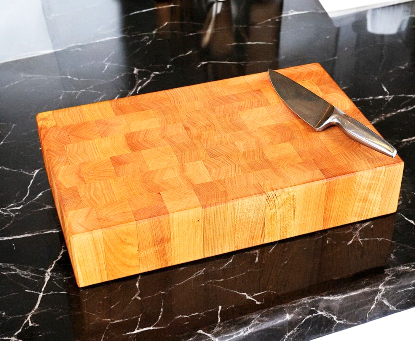 Hackblock aus Stirnholz Kirschbaum mit Messer auf Arbeitsplatte.