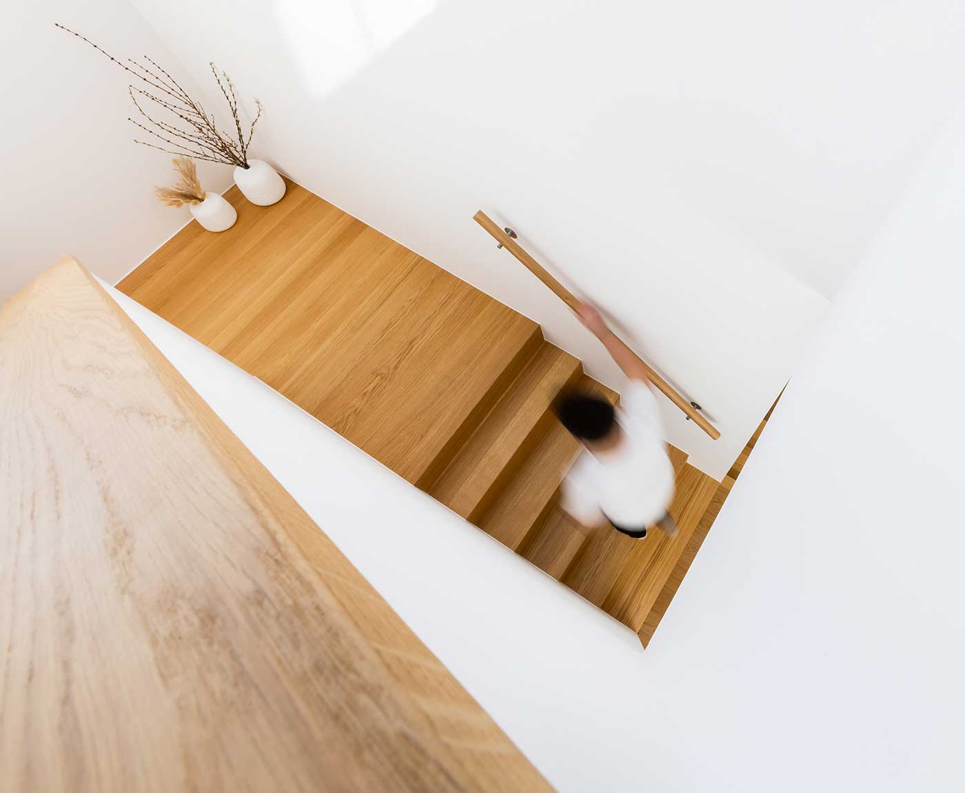 Treppe mit Handlauf aus Holz und Person von oben